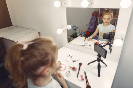 Cute little blogger with cosmetics recording video at homeの写真素材