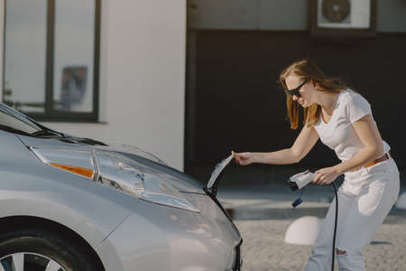 Woman charging electro car at the electric gas stationの写真素材