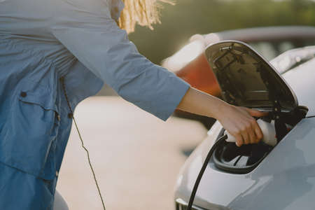 Woman charging electro car at the electric gas stationの写真素材