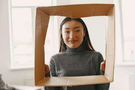 Asian young woman looking through cardbox in new flatの写真素材