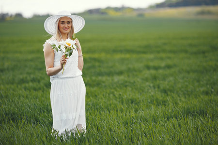Woman in elegant dress standing in a summer fieldの写真素材