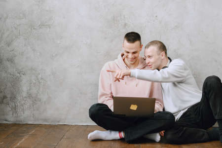 Gay couple consulting their travel plans together with a laptopの写真素材