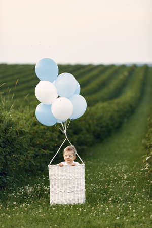 Little child sitting in the basket with balloonsの写真素材