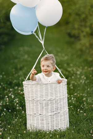 Little child sitting in the basket with balloonsの写真素材