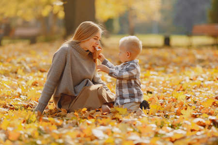 Mother with little son sitting in a autumn fieldの写真素材