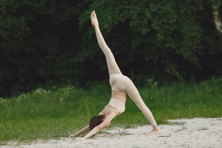 Woman practicing advanced yoga in a beachの写真素材