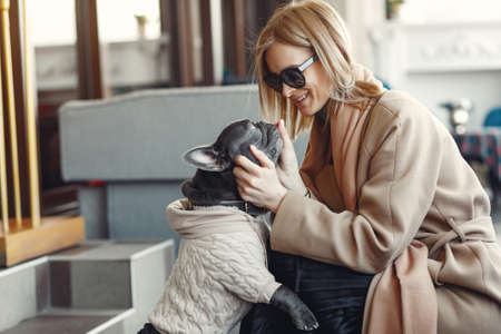 Elegant woman in a brown coat with black bulldogの写真素材