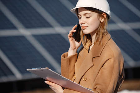 Woman technician at solar station talking on phoneの写真素材