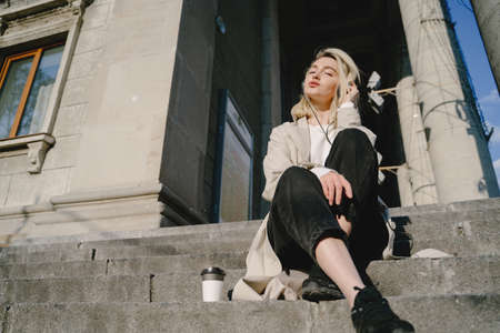 Blonde with headphones sitting on a stairsの写真素材