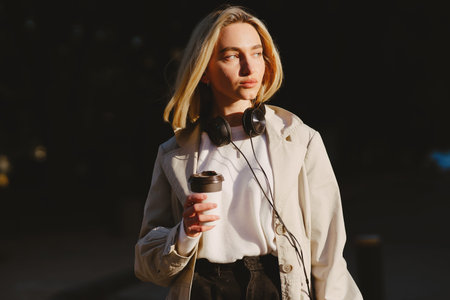 Blonde walks in summer city with cup of coffee