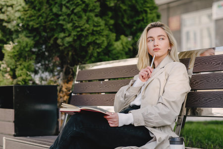Blonde sitting on a bench with notebookの写真素材