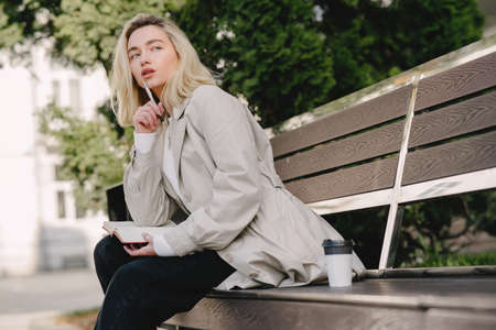 Blonde sitting on a bench with notebookの写真素材