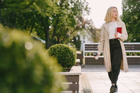 Blonde in a summer city with cup of coffeeの写真素材