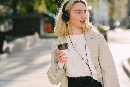 Blonde walks in summer city with cup of coffee