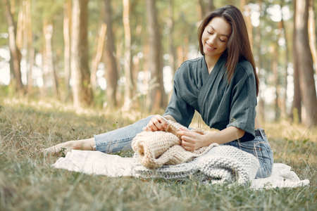 Girl sitting in a summer park and knittingの写真素材