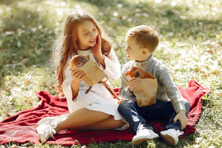 Cute little children sitting in a park with breadの写真素材