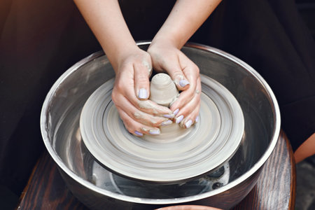 People making a vaze from a clay on a potterys machine