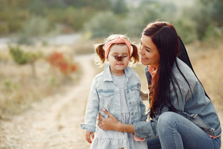 Mother with little daughter playing in a autumn fieldの写真素材