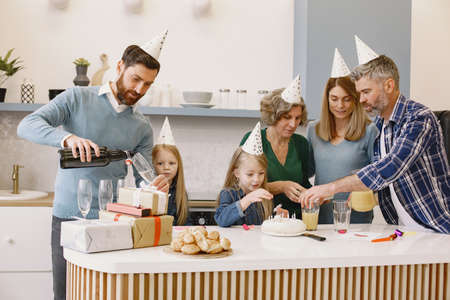 Family celebrating birthday of their grandmother in the kitchenの写真素材