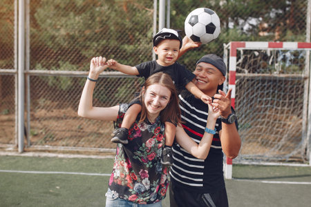 Family with little son playing a football