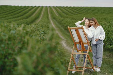Elegant and beautiful girls painting in a fieldの写真素材