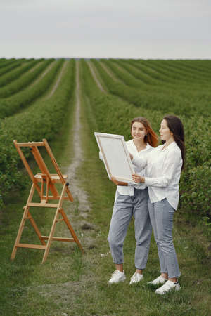 Elegant and beautiful girls painting in a fieldの写真素材