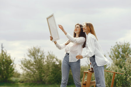 Elegant and beautiful girls painting in a field