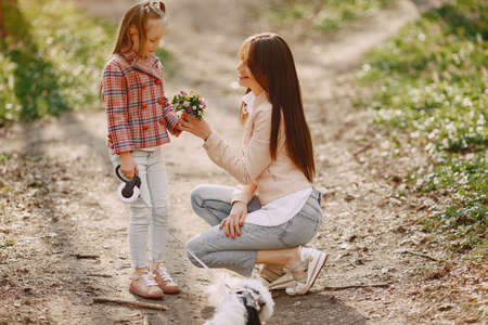 Mother with daughter in a spring forest with dogの写真素材