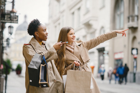 Happy mixed girls walking the street with shopping bags