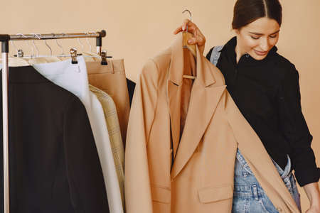 Woman in a studio with many clothesの写真素材