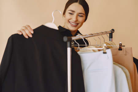 Woman in a studio with many clothesの写真素材
