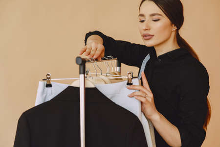 Woman in a studio with many clothesの写真素材