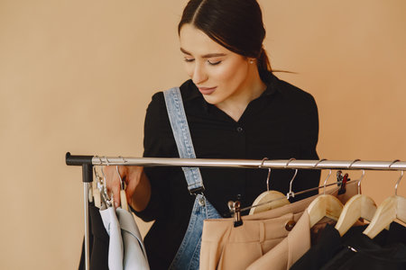 Woman in a studio with many clothesの写真素材