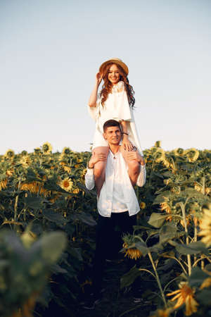 Beautiful and stylish couple in a field wirh sunflowersの写真素材