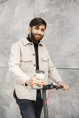 Positive smiling man riding a kick scooter