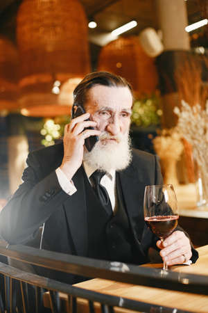 Elegant old man is resting in restaurantの写真素材