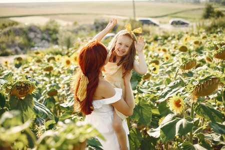 Beautiful and cute family in a field wirh sunflowersの写真素材