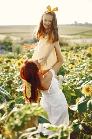 Beautiful and cute family in a field wirh sunflowersの写真素材