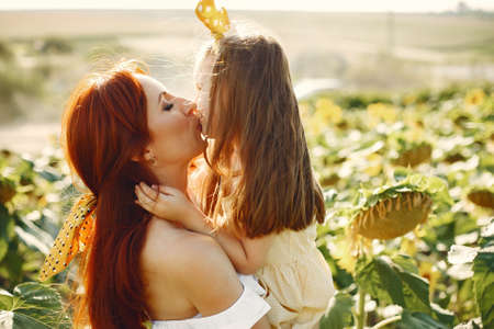 Beautiful and cute family in a field wirh sunflowersの写真素材