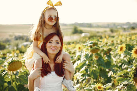 Beautiful and cute family in a field wirh sunflowersの写真素材