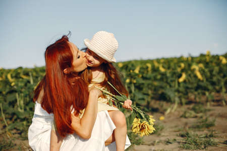 Beautiful and cute family in a field wirh sunflowersの写真素材