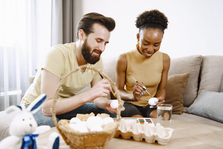 African woman and caucasian man paint easter eggs