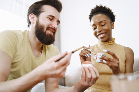 African woman and caucasian man paint easter eggsの写真素材