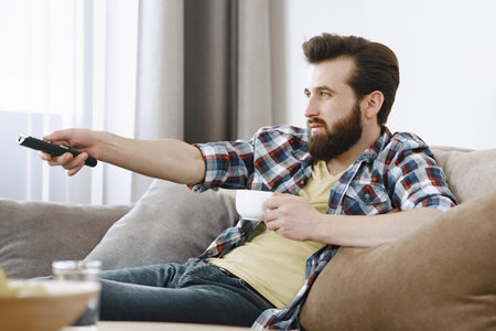 Man drinking coffee and watching TV on couch