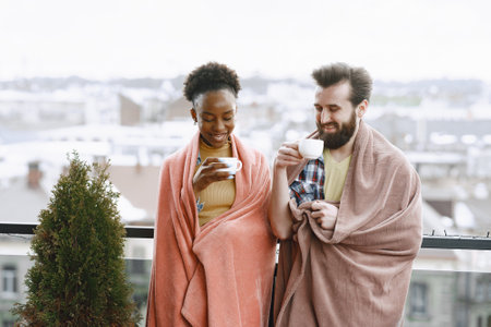Man and woman on terrace in a blanket drinking coffeeの写真素材