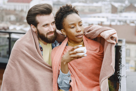 Man and woman on terrace in a blanket drinking coffeeの写真素材