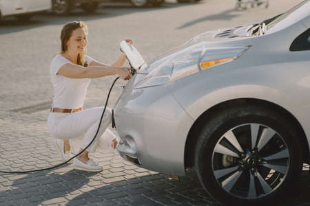 Woman charging electro car at the electric gas stationの写真素材