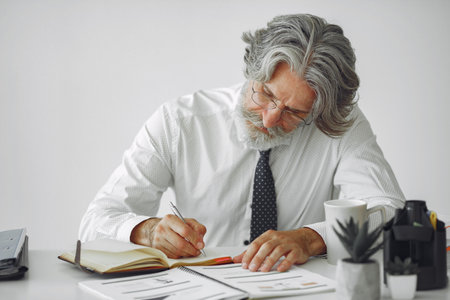 Handsome pensive mature businessman sitting in the officeの写真素材