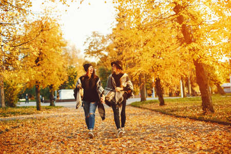 two young girls walk around the city in the autumn city and parkの写真素材