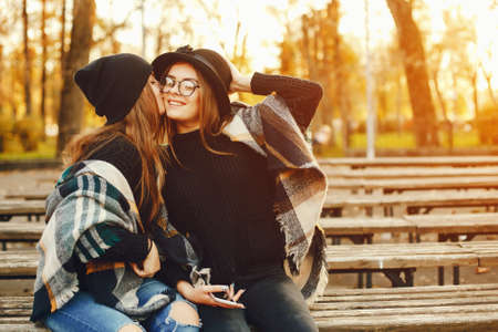 two young girls walk around the city in the autumn city and parkの写真素材